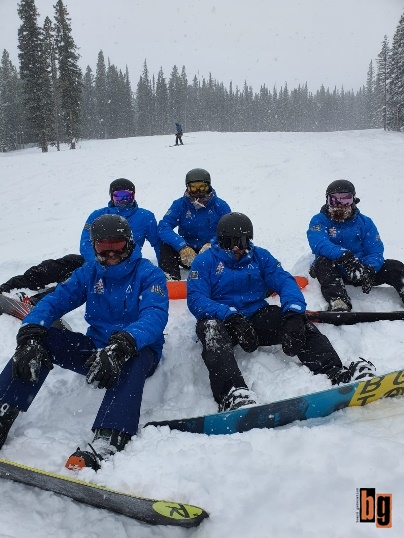 Five snowboarders sitting in the snow